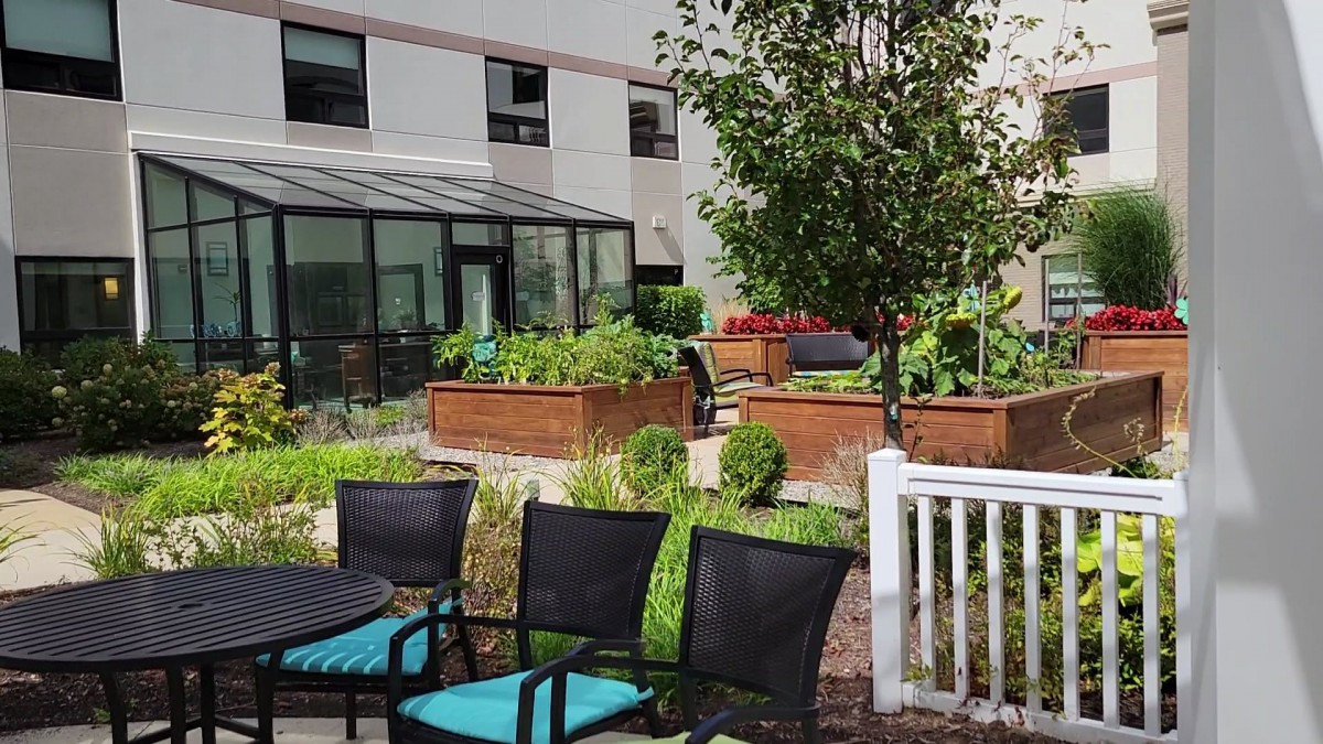 A serene outdoor garden area with raised planters and patio seating outside a building.