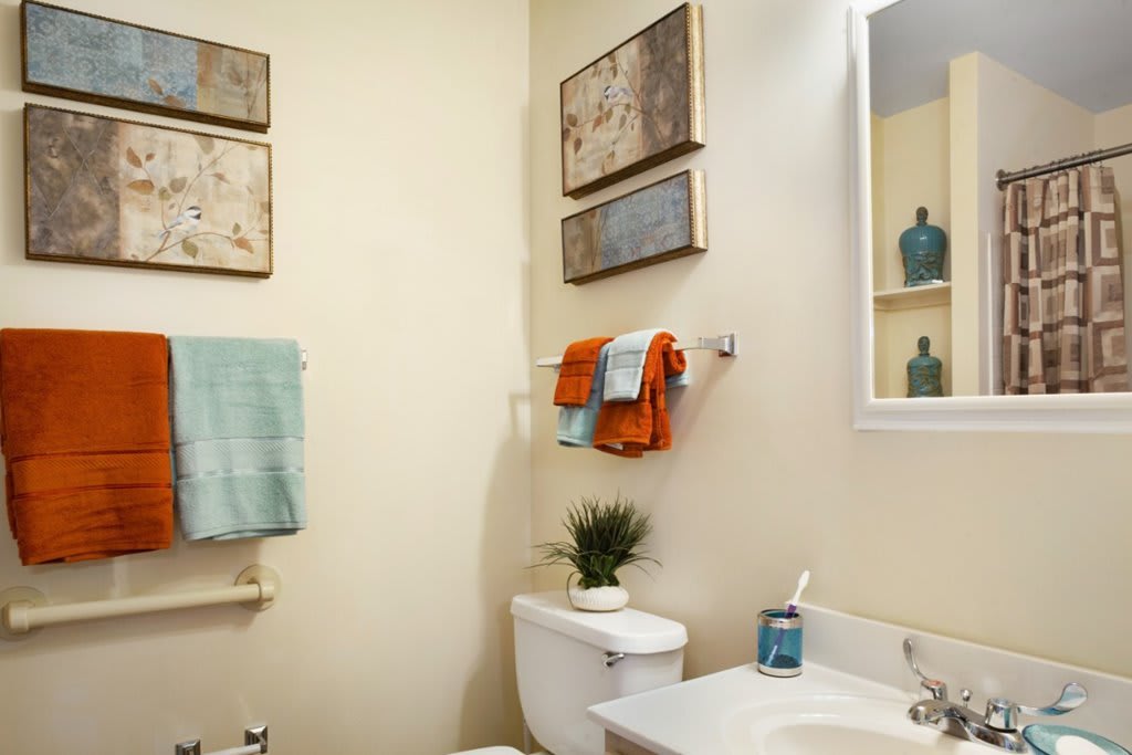 A neatly organized bathroom with colorful towels and decorative wall art.
