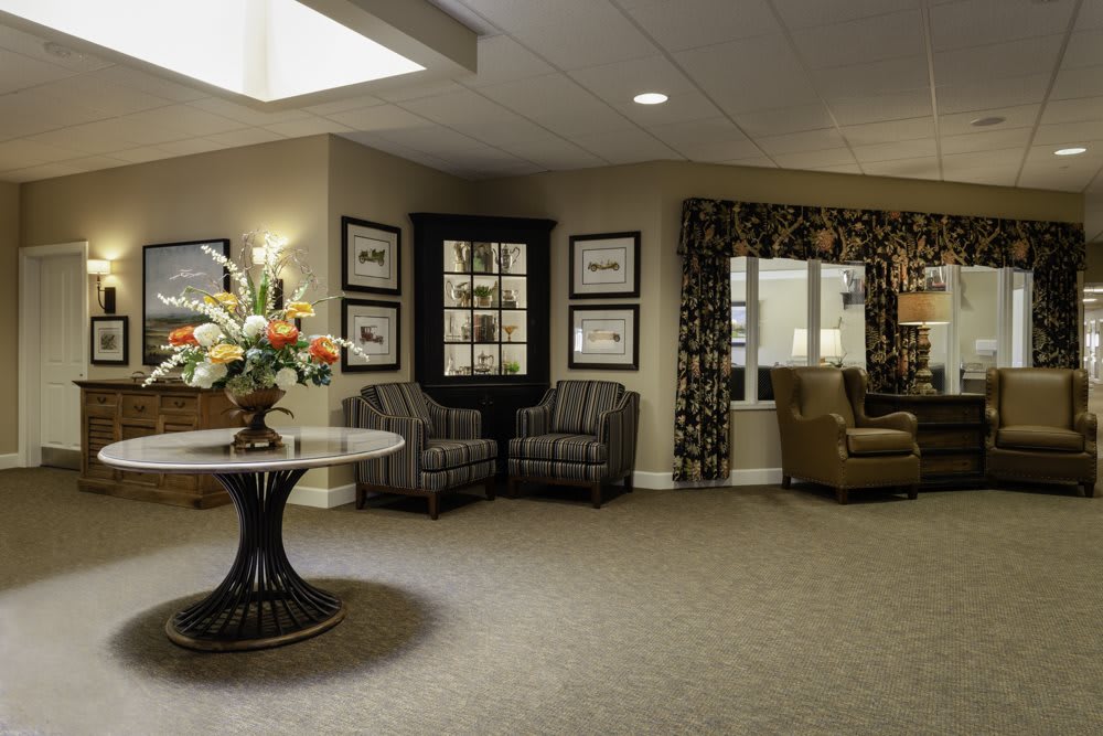 A well-decorated lobby area featuring comfortable seating, framed artwork, and a centerpiece table with a floral arrangement.