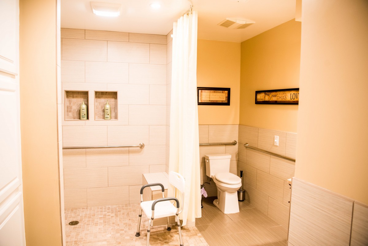 An accessible bathroom with a shower area, equipped with a curtain and grab bars.