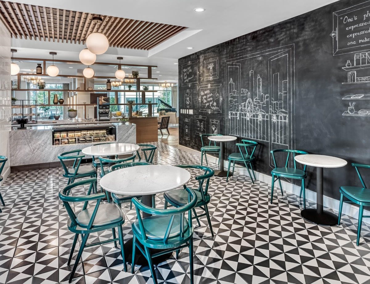 A modern restaurant interior with geometric flooring and green chairs.