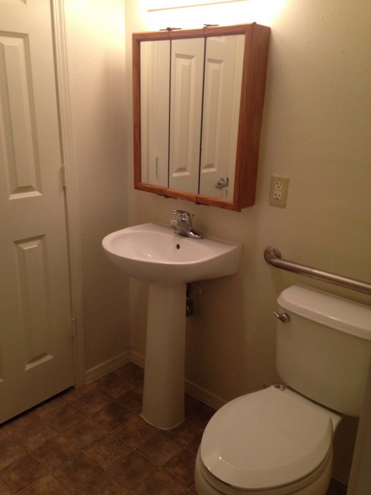 A minimalist bathroom with a pedestal sink and wall-mounted mirror.