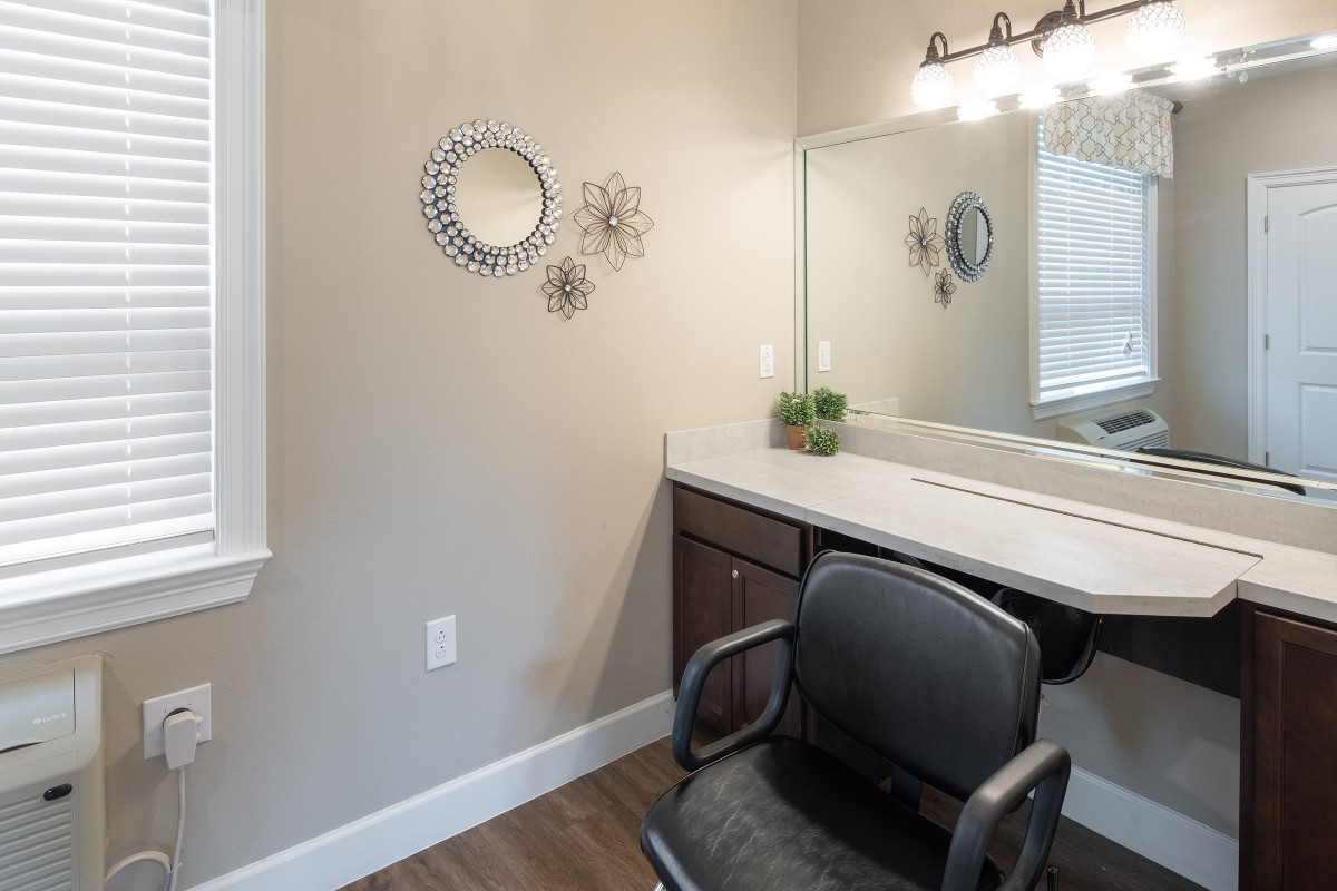 A stylish vanity area with a mirror, chair, and decorative wall elements.