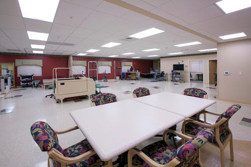 A spacious interior of a rehabilitation center featuring tables and chairs, designed for group activities.