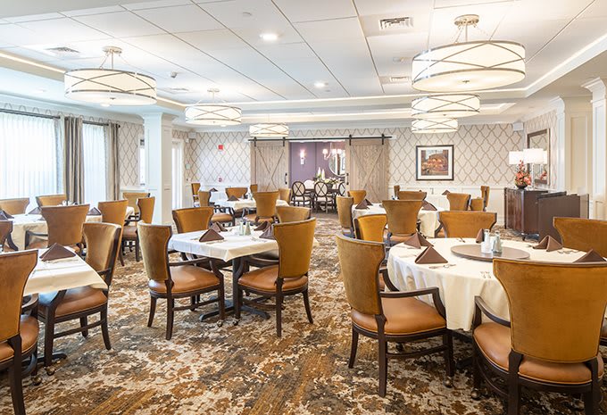 An elegant dining room with neatly arranged tables and chairs, featuring stylish lighting and decor.