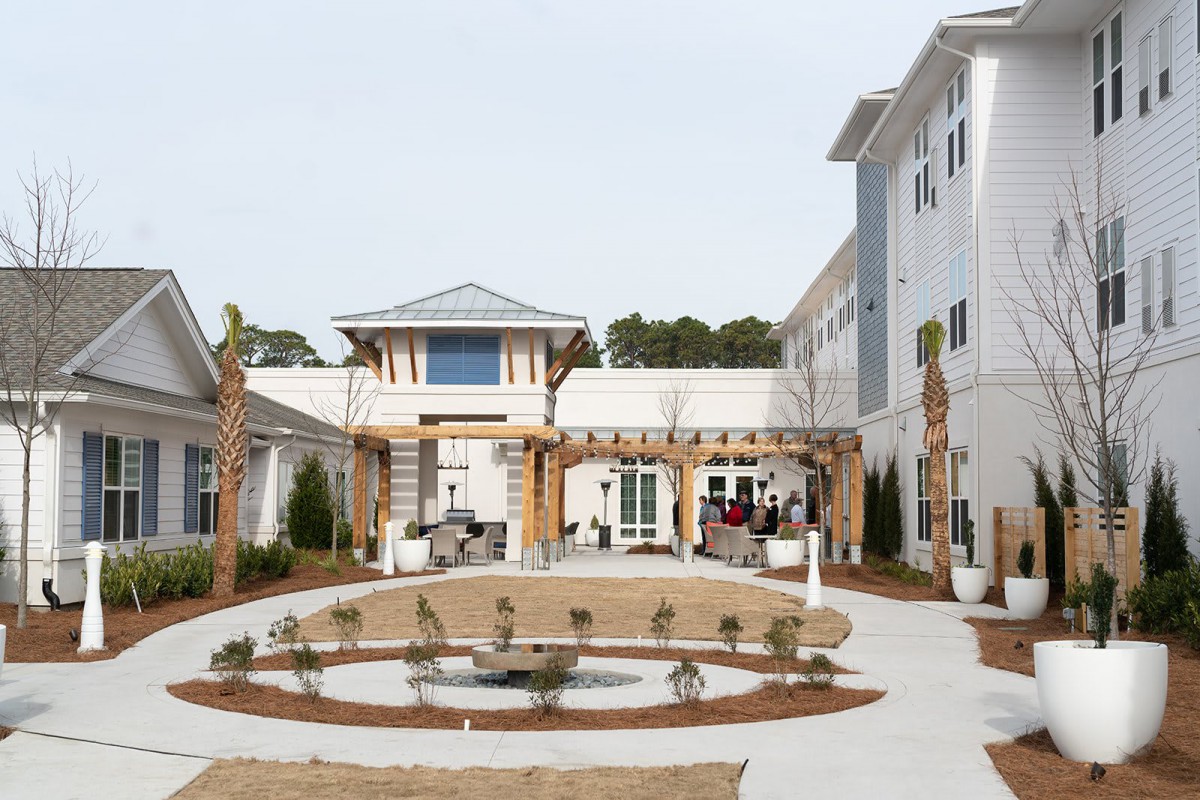 A modern building with a landscaped courtyard featuring palm trees and a circular garden path.