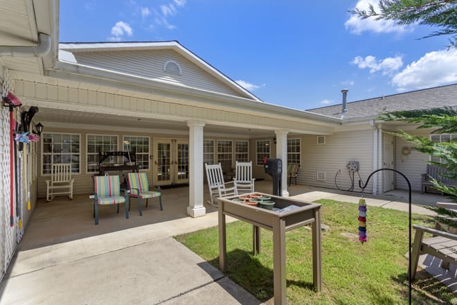 A spacious backyard patio with outdoor seating and a grill under a clear blue sky.