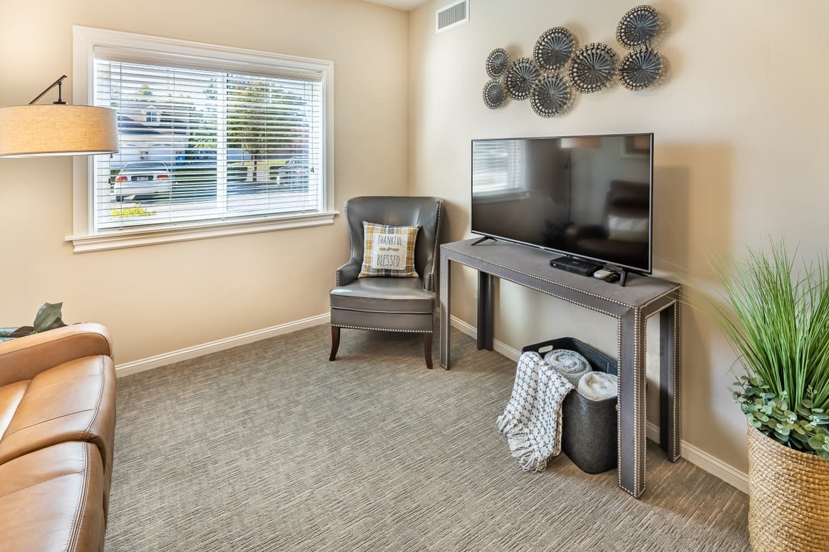 A modern living room with a television, armchair, and decorative wall art.