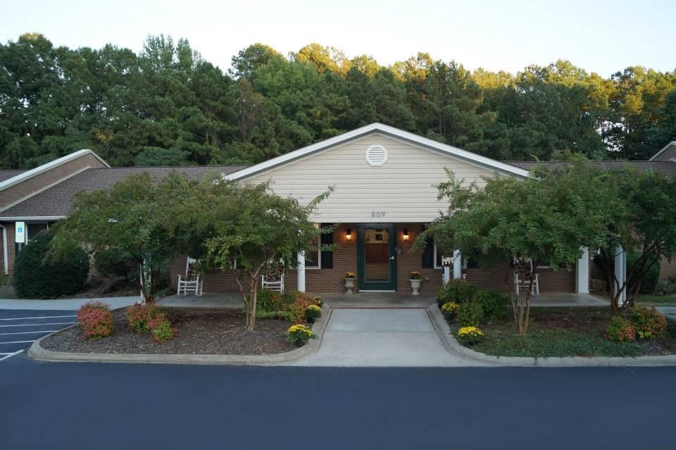 A building with a landscaped entrance surrounded by trees.
