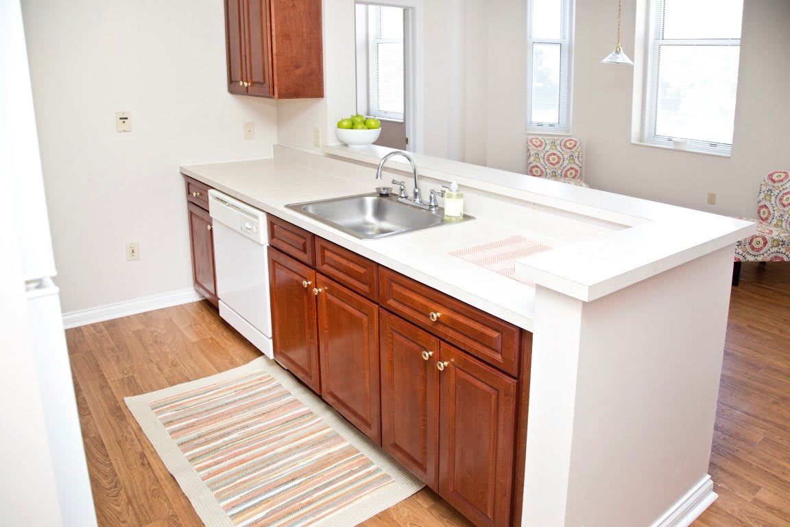 A modern kitchen with wooden cabinets, a white countertop, and a built-in sink.