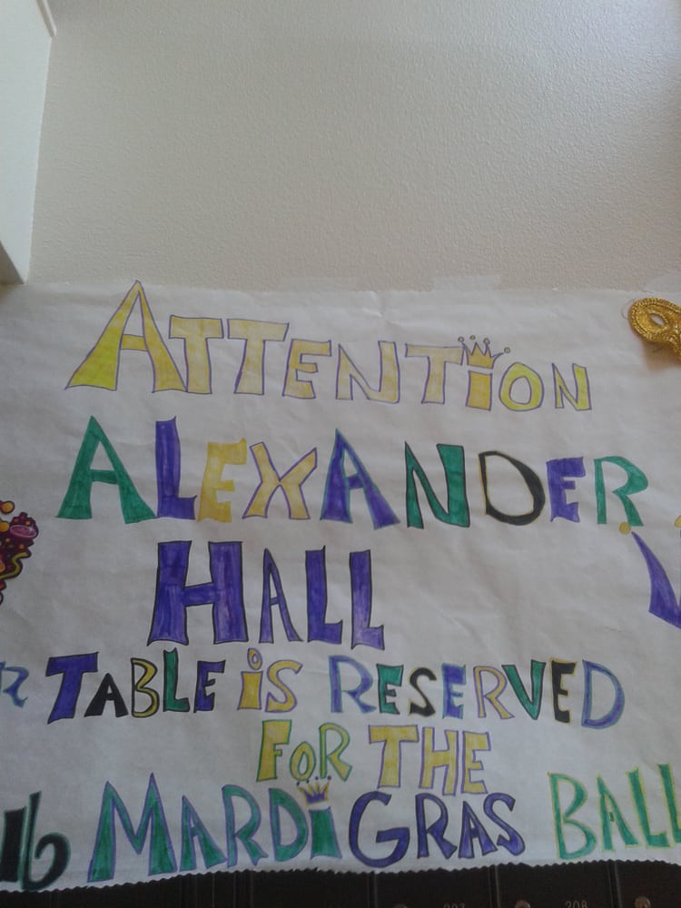 A colorful handwritten sign announcing a reserved table for Alexander Hall.