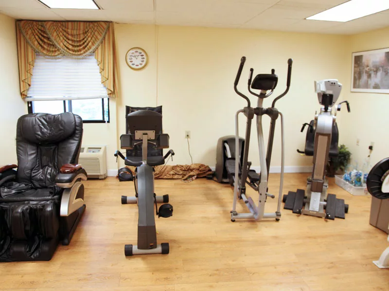 A small gym with various exercise machines, including a stationary bike and elliptical.
