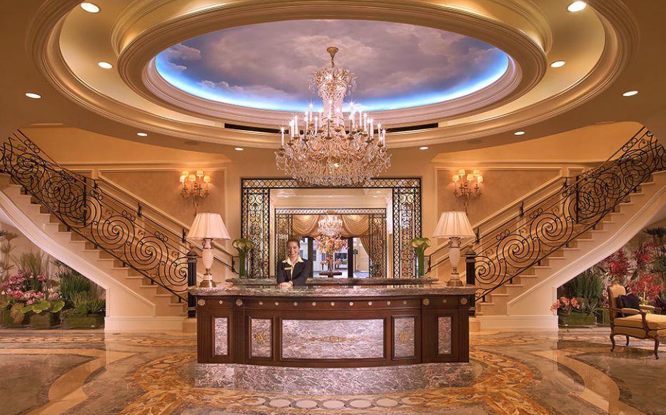 A luxurious hotel lobby featuring a grand chandelier and elegant staircase.