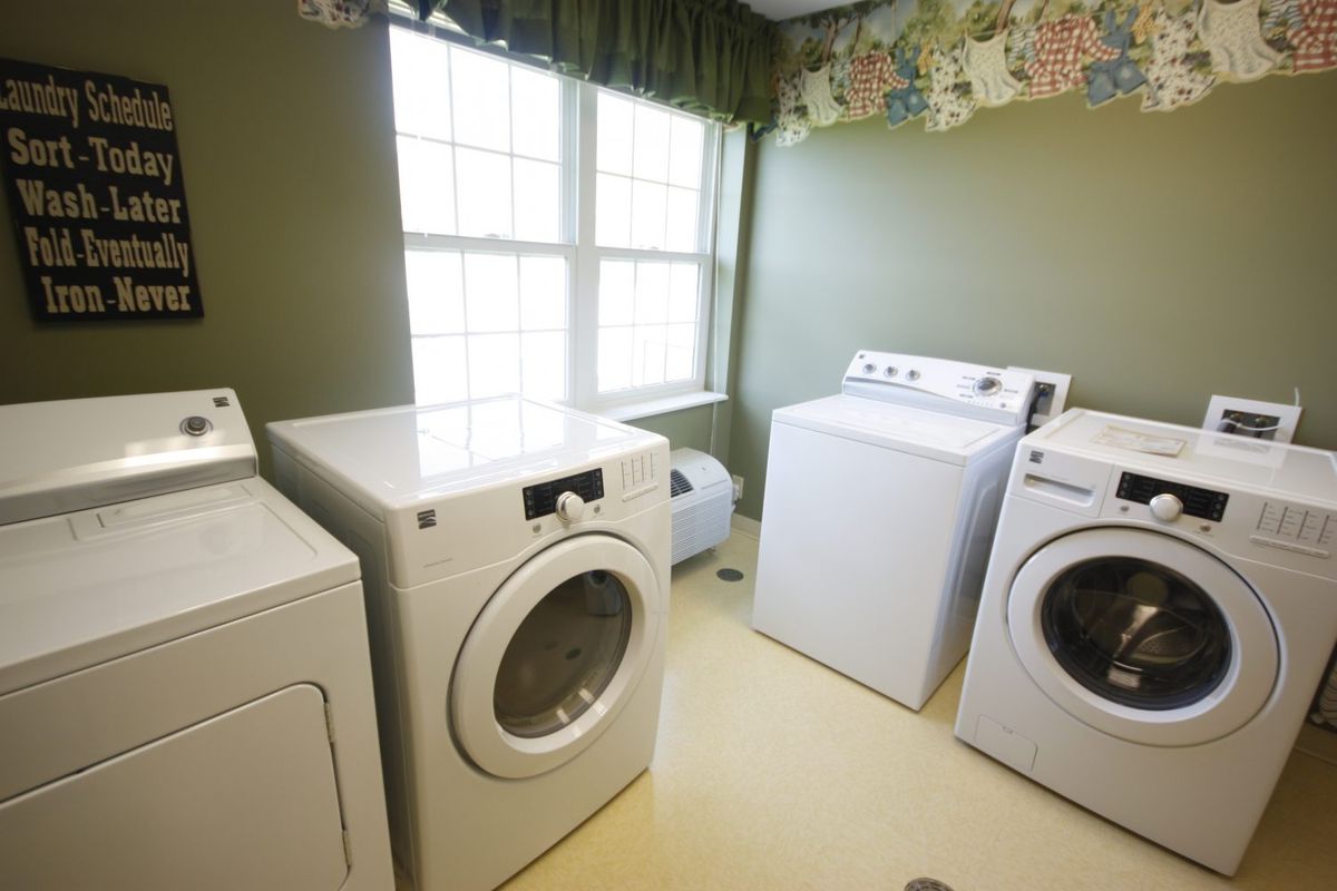 A well-lit laundry room with multiple washing machines and dryers.
