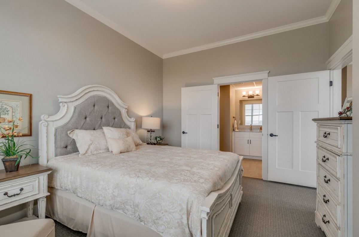 A well-decorated bedroom with elegant furniture and a view into an adjoining bathroom.