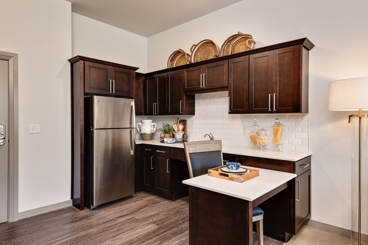A modern kitchen with dark wood cabinets and stainless steel appliances.