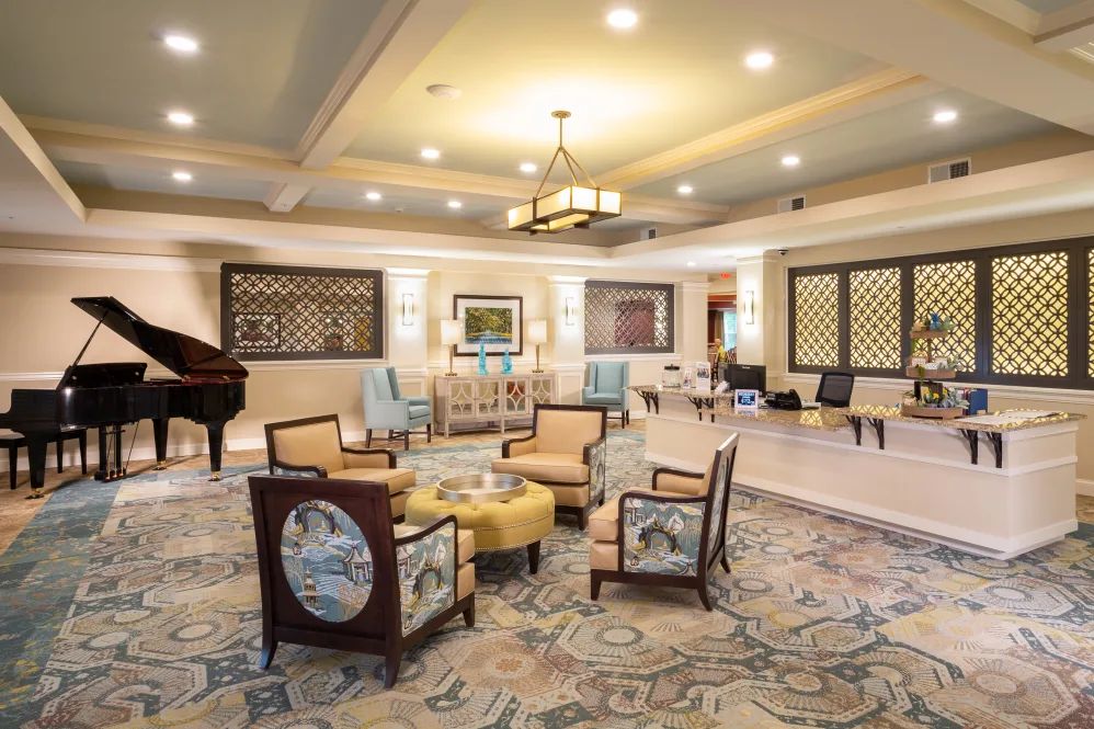 A spacious and elegantly decorated living room featuring a seating area with plush chairs, a decorative carpet, and ambient lighting.