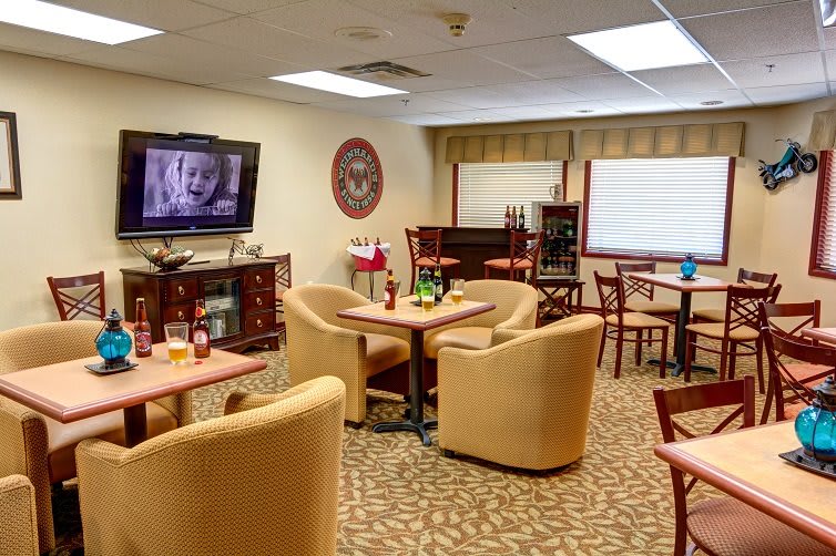 A cozy lounge area featuring comfortable seating, a television, and several tables.