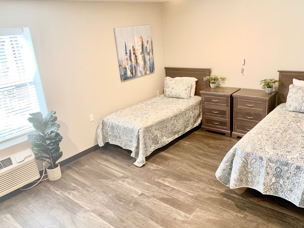 A minimalist bedroom featuring two twin beds with wooden furniture and a simple decor.