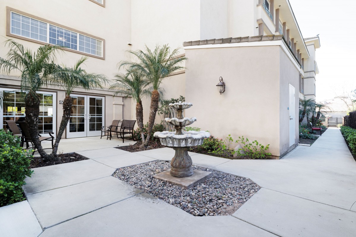 A serene courtyard with a central fountain surrounded by palm trees and seating areas.