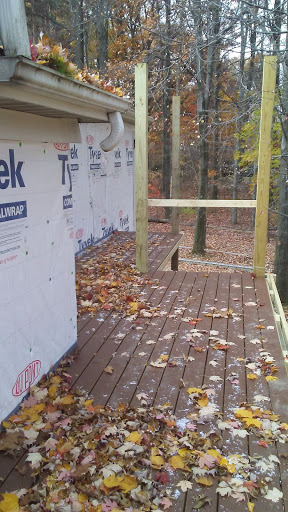 A partially finished outdoor deck surrounded by autumn leaves.