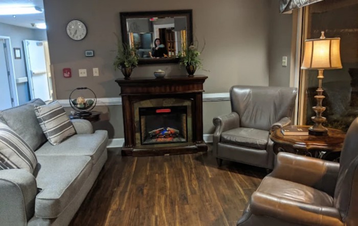 A cozy living room with a fireplace, sofa, and armchairs.