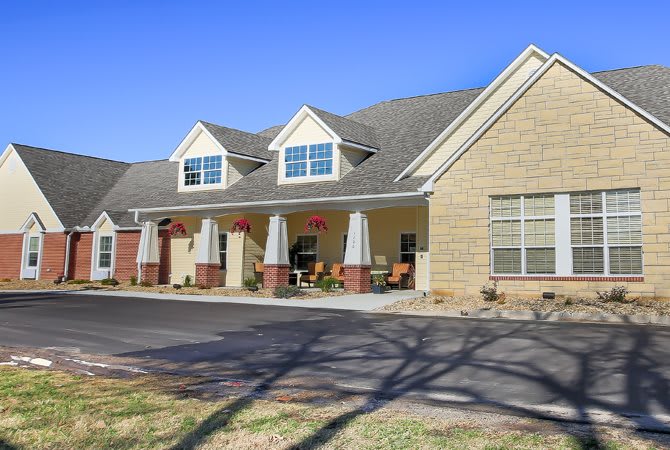 A suburban residential building with a porch and multiple windows on a sunny day.