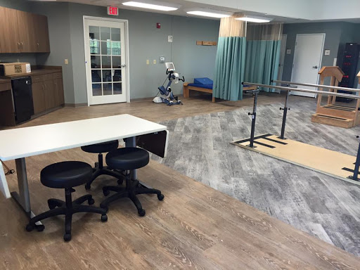 A spacious therapy room equipped with tables, chairs, and exercise equipment for rehabilitation.