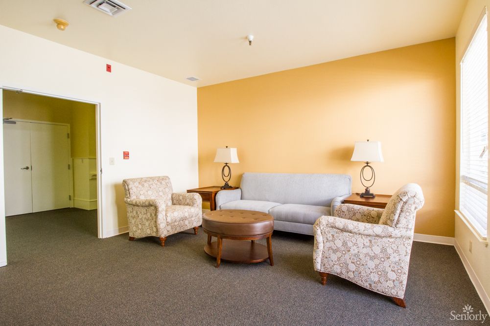 A cozy living room with a sofa, armchairs, and a coffee table set against an orange accent wall.