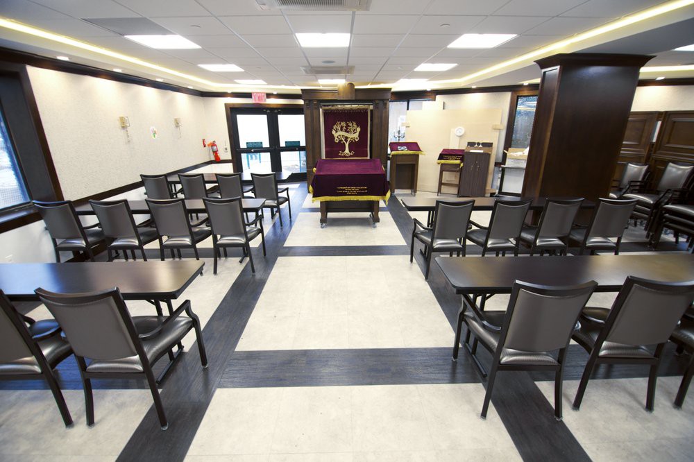 A neatly arranged synagogue interior with rows of chairs and a central prayer area.
