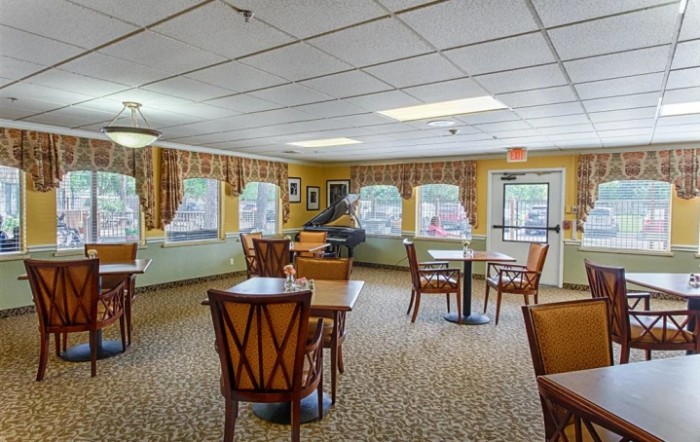 A cozy dining area with wooden tables and chairs, large windows, and tasteful decor.