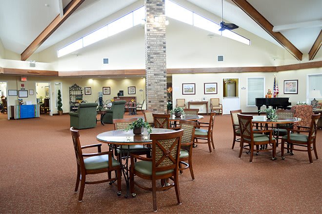 Spacious lounge area with tables and chairs under a high ceiling.