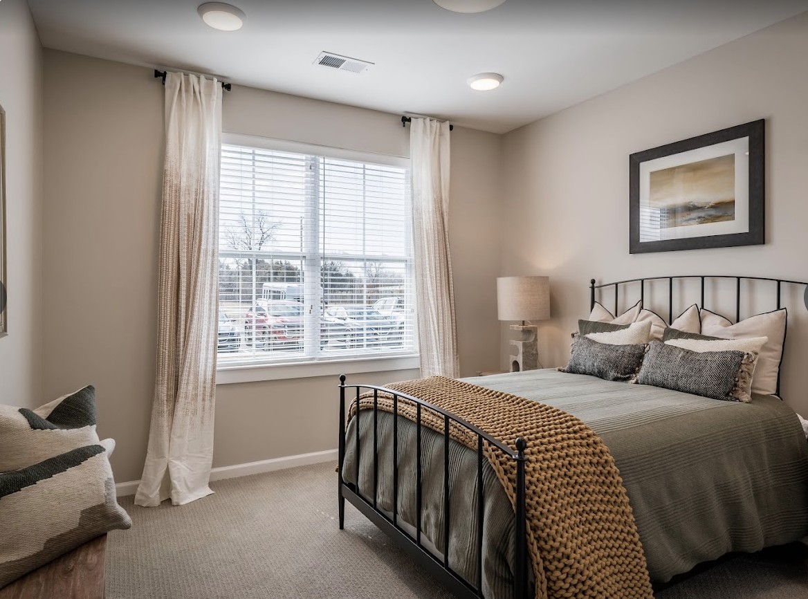 Cozy bedroom interior with a metal frame bed and large window.