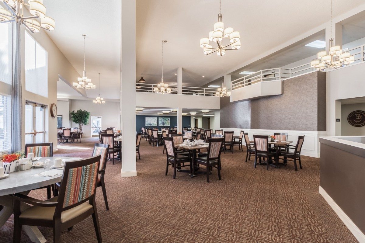 A spacious dining area with elegant chandeliers and neatly arranged tables and chairs.