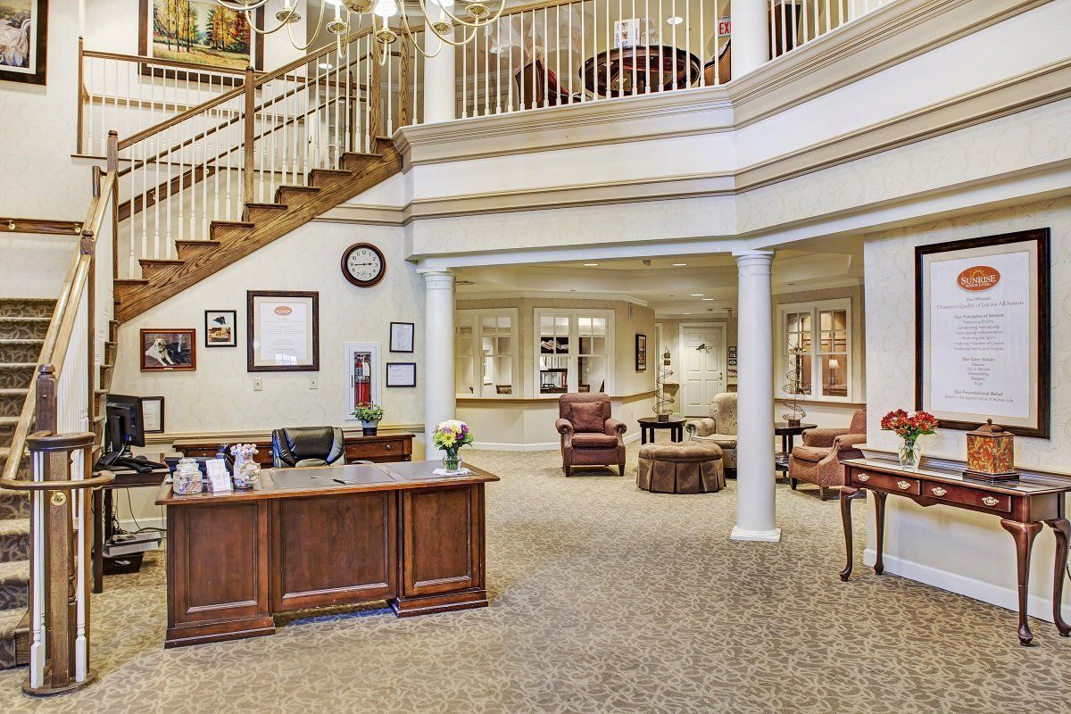 A spacious lobby with a reception desk, comfortable seating, and ornate staircases.