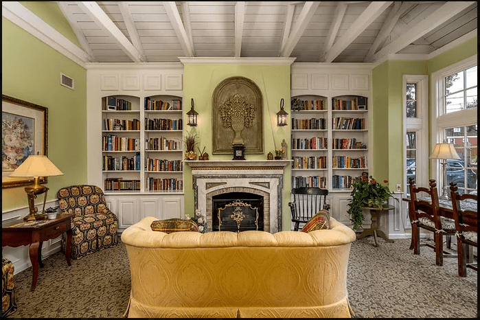A cozy living room with a central fireplace, surrounded by built-in bookshelves and a plush sofa.