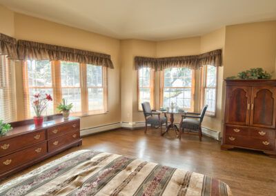 A cozy bedroom interior with large windows and elegant furnishings.