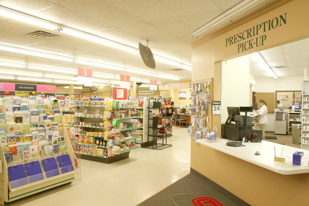 Interior of a pharmacy store with shelves stocked with products and a checkout counter.