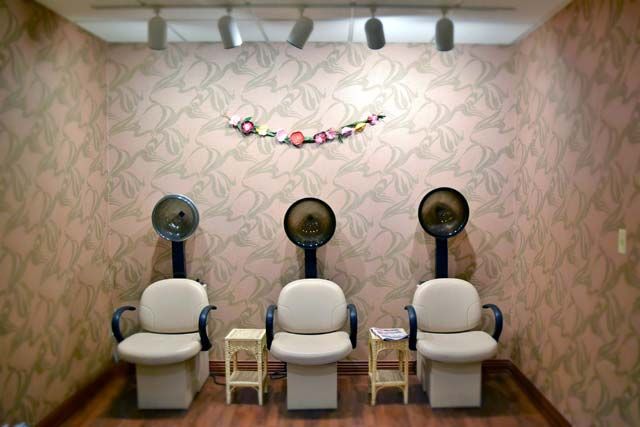 A cozy hair salon setup with three drying chairs under wall-mounted hair dryers.