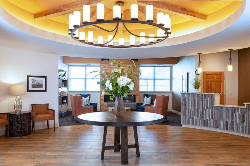 A beautifully designed lobby with a central table displaying flowers, elegant seating arrangements, and a large chandelier.