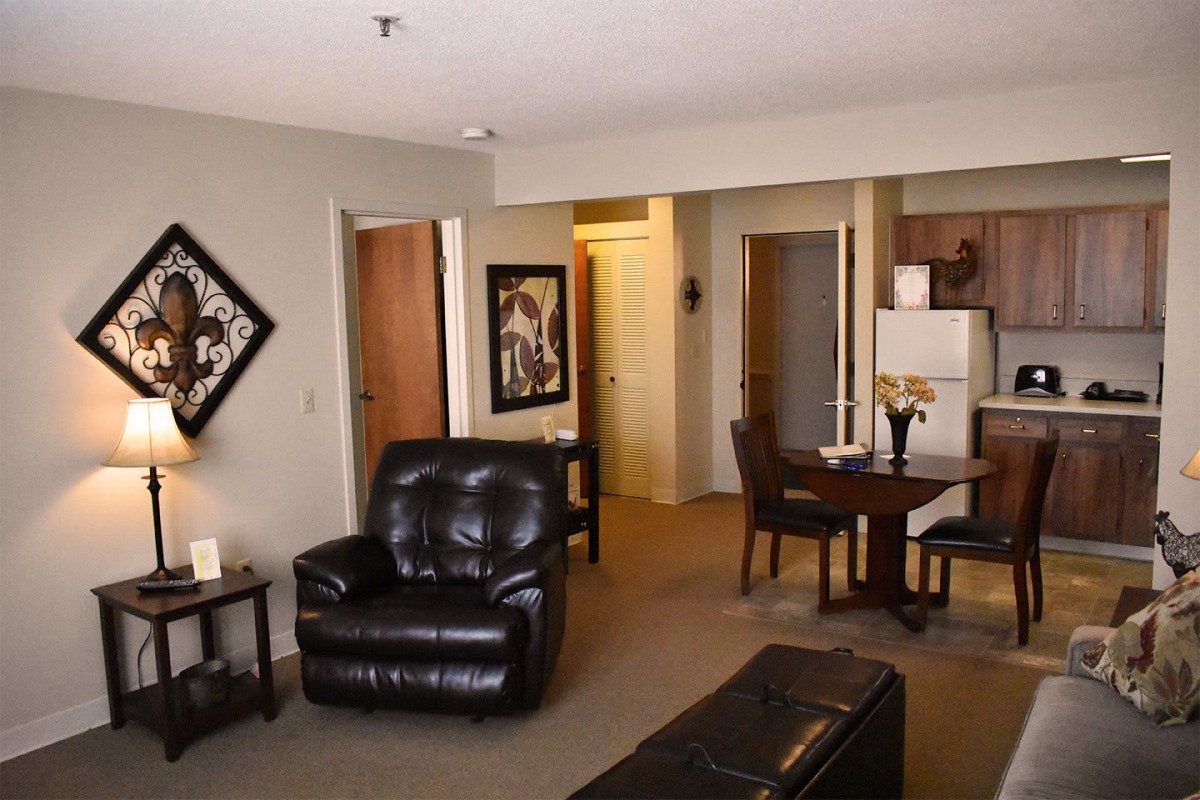 A cozy living space with leather furniture and an open dining area connected to the kitchen.