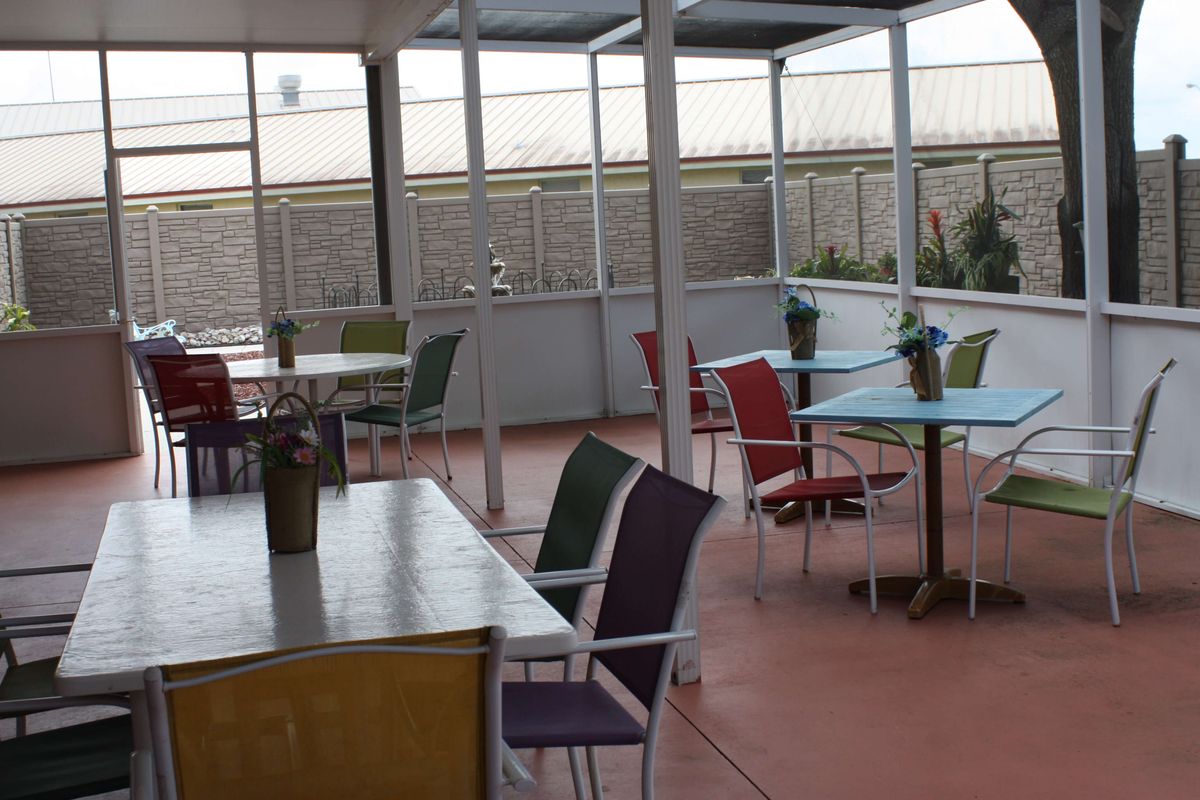 An empty outdoor patio with colorful chairs and tables, ready for guests.