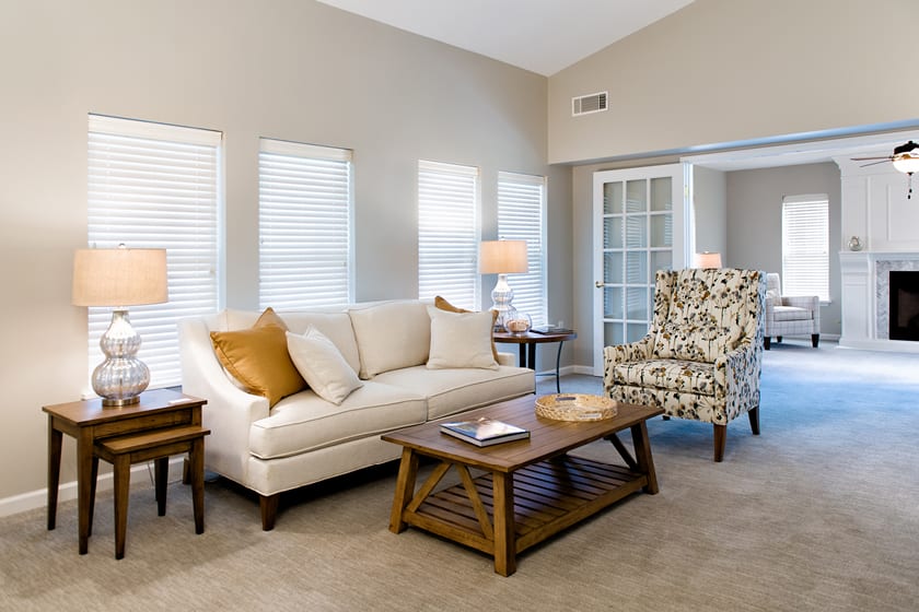 A cozy living room with neutral tones, featuring a sofa, patterned armchair, and coffee table.