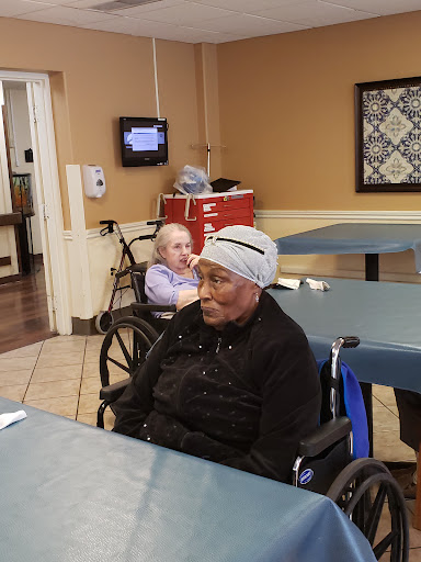 Two elderly individuals in a care facility, sitting in wheelchairs.
