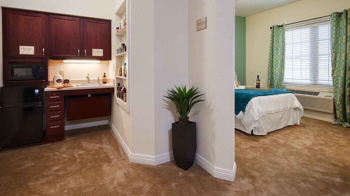 A cozy bedroom corner with a plant and view into a bathroom area.