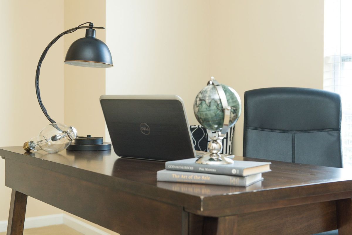A tidy office desk setup with a laptop, globe, and books.