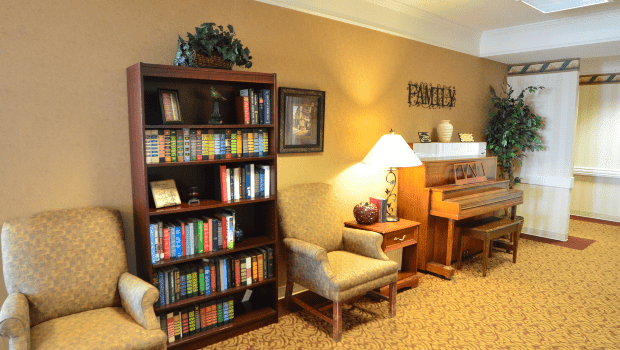 Cozy living room with a bookshelf, armchair, and piano.