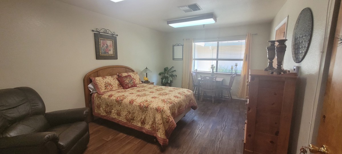 A cozy bedroom with a double bed, wooden floors, and a window letting in natural light.