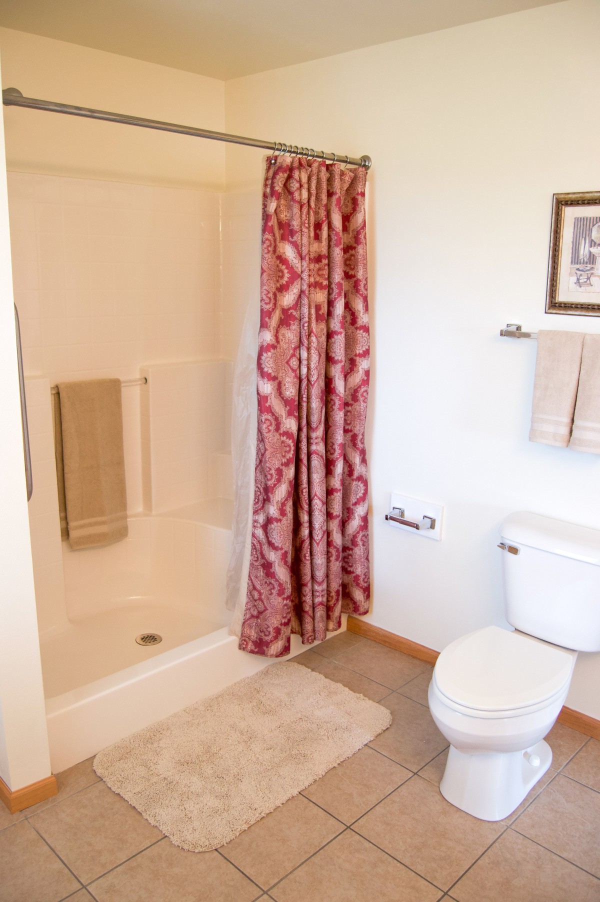 A well-organized bathroom with a shower, decorative curtain, and neatly arranged towels.
