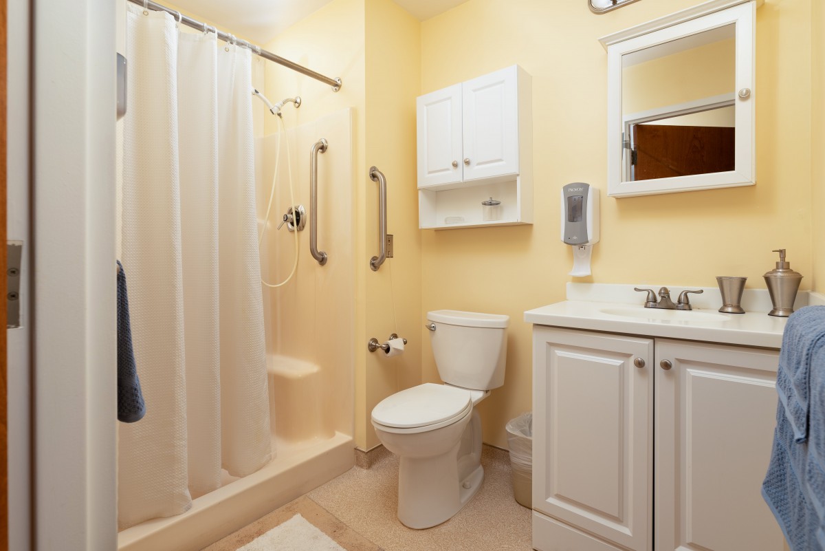 A clean and well-organized bathroom with a shower, toilet, sink, and storage cabinet.